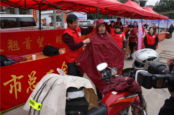 梧州市總工會(huì)的黨員義工們?cè)谑袞|出口春運(yùn)服務(wù)站助力“摩托大軍”平安返鄉(xiāng)，幫助他們檢查車(chē)輛和行李，穿上雨衣。--黃賀峰攝.j